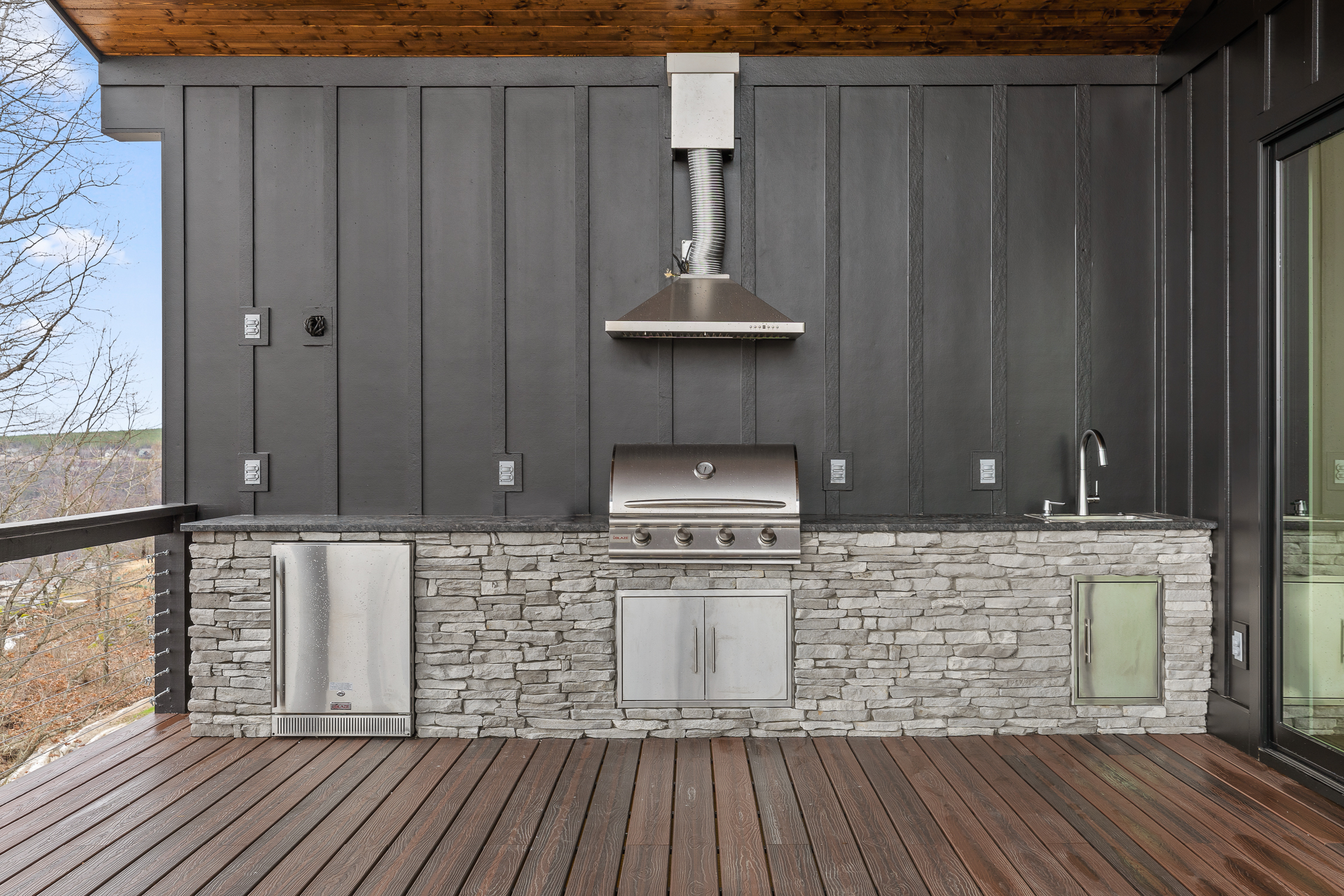 Outdoor kitchen in a grey ledgestone from Horizon Stone with dark grey accent wall.